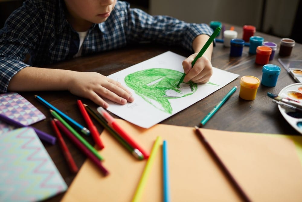 Little boy drawing picture of green monster