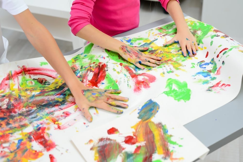 Two kids painting with hands